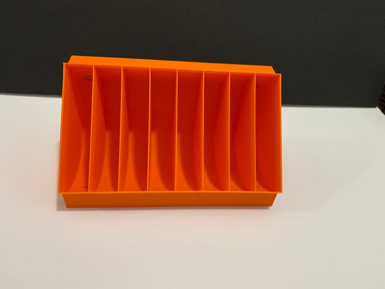 K&ouml;nnte beinhalten: Orangefarbener Plastik-Organizer mit acht F&auml;chern. Der Organizer ist f&uuml;r die Aufbewahrung von kleinen Gegenst&auml;nden wie Stiften, Bleistiften oder Bastelbedarf konzipiert.