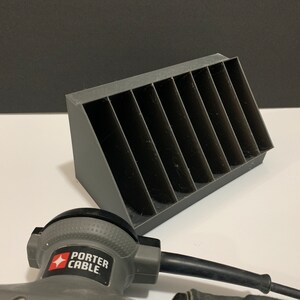 K&ouml;nnte beinhalten: Ein grauer Plastik-Organizer mit acht F&auml;chern zur Aufbewahrung von Kleinteilen. Der Organizer ist abgewinkelt und hat eine strukturierte Oberfl&auml;che. Ein graues Elektrowerkzeug mit dem Text "PORTER CABLE" befindet sich im Vordergrund.