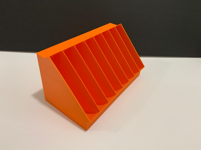 K&ouml;nnte beinhalten: Orangefarbener Plastik-Organizer mit sieben F&auml;chern, abgewinkelt, um einen abgestuften Effekt zu erzeugen.