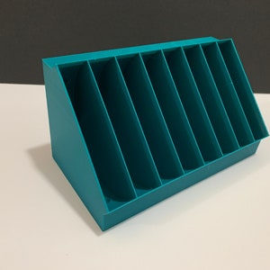 K&ouml;nnte beinhalten: Tealblauer Plastik-Organizer mit sieben F&auml;chern. Der Organizer ist abgewinkelt und hat eine rechteckige Form.