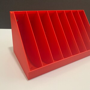 K&ouml;nnte beinhalten: Ein roter Plastik-Organizer mit acht F&auml;chern, die f&uuml;r einen einfachen Zugriff abgewinkelt sind. Der Organizer ist ideal zum Aufbewahren von kleinen Gegenst&auml;nden wie Bastelbedarf, Schmuck oder B&uuml;robedarf.