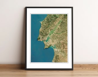 May include: A satellite image of a coastal area with a large body of water and a peninsula. The peninsula is covered in green vegetation and the water is a deep blue.