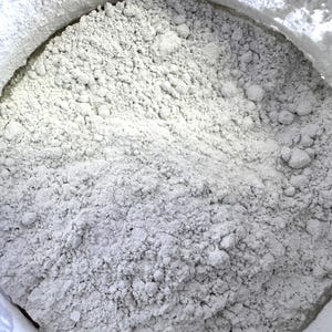 May include: A close-up view of a white powder in a container. The powder is fine and has a slightly grainy texture.