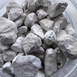 May include: A close-up view of a bowl filled with white, irregularly shaped rocks. The rocks are smooth and have a slightly rough texture.