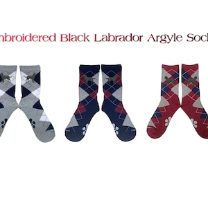 May include: Three pairs of black Labrador argyle socks. The socks are in three different color combinations: gray and navy blue, red and navy blue, and gray and red. Each sock features a black Labrador silhouette.