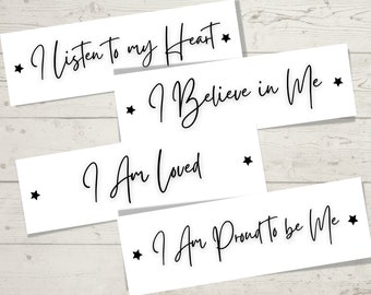 May include: Four white rectangular signs with black text and a black star on each side. The signs read "I listen to my Heart", "I Believe in Me", "I Am Loved", and "I Am Proud to be Me".