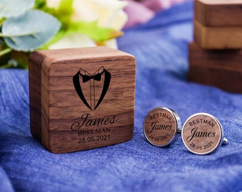 Op de afbeelding: Een houten doos met een smokingontwerp en de tekst "James Best Man 28.05.2021" erop gegraveerd. Twee zilveren manchetknopen met de tekst "Best Man James 28.05.2021" erop gegraveerd.