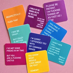 May include: A collection of square cards in various colors, each with bold white text. The cards feature humorous and sarcastic phrases like "FUCK THAT" and "I'M SORRY I OFFENDED YOU WITH MY COMMON SENSE."