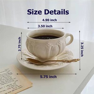 May include: White ceramic teacup and saucer set with gold trim. The cup is 4.90 inches wide, 3.50 inches tall, and 2.75 inches deep. The saucer is 5.75 inches wide and 3.25 inches tall.