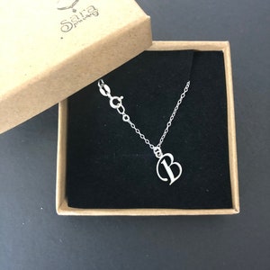 May include: A silver necklace with a cursive letter 'B' pendant in a black velvet box. The box is labelled "Sara Jewelry".
