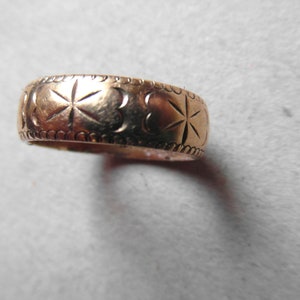 May include: A gold band ring with a decorative design of stars and hearts.