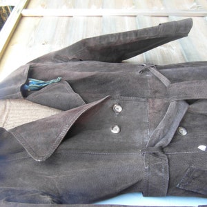May include: A brown suede jacket with a long, flowing design. The jacket has a large collar, a belt, and two buttons on the front.