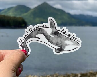 Può includere: Un adesivo in acquerello bianco e nero di un'orca con il testo "all good things are wild and free" intorno all'orca.