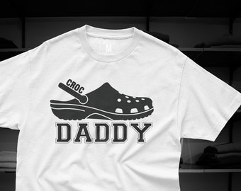 May include: White t-shirt with a black graphic of a Croc shoe and the text "CROC DADDY".