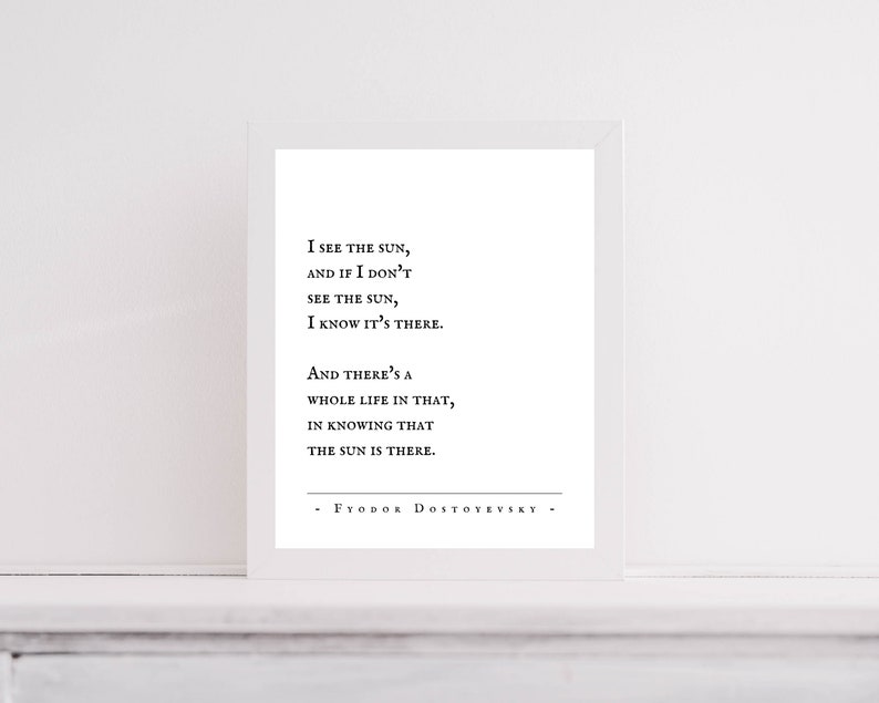 Op de afbeelding: Zwart-witte typografieprint met een citaat van Fjodor Dostojevski: "Ik zie de zon, en als ik de zon niet zie, weet ik dat hij er is. En daarin ligt een heel leven, te weten dat de zon er is."