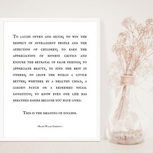 Puede incluir: Una impresi&oacute;n en blanco y negro con una cita de Ralph Waldo Emerson sobre el significado del &eacute;xito. La cita est&aacute; impresa en un fondo blanco y enmarcada en un marco blanco. La impresi&oacute;n est&aacute; sobre una mesa junto a un jarr&oacute;n de flores secas.