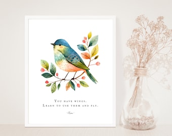 Puede incluir: Una pintura de acuarela de un pájaro azul posado en una rama con bayas rosas y hojas verdes. La cita "You have wings. Learn to use them and fly. - Rumi" está impresa debajo del pájaro.