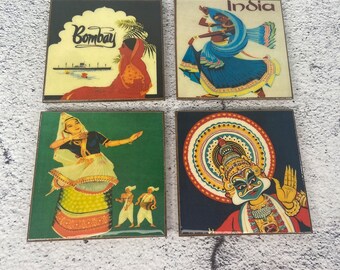 May include: Set of four square coasters featuring colorful images of Indian culture. The coasters feature images of dancers, a traditional Indian temple, and the word "Bombay".