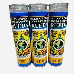 May include: Three glass candle jars with blue and yellow labels. The labels feature a tarot card image of the Wheel of Fortune with the text "Rueda" and "De Wereld" in Spanish and Dutch. The text "Fixed Candle" and "Reladora Compues" is also on the label.