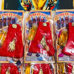 May include: Six small red velvet pouches with gold charms, small glass bottles, and colourful stones. The pouches are labelled "AMULETO" and "MANO PODEROSA".