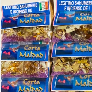 Puede incluir: Una pila de seis pequeñas bolsas de plástico transparente llenas de una mezcla de hierbas secas y cristales. Cada bolsa tiene una etiqueta azul con el texto "Corta Maldad" en letras blancas. La etiqueta también tiene una imagen roja y rosa de un murciélago.