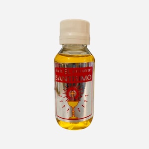 May include: A small, clear glass bottle with a white cap filled with a yellow liquid. The bottle has a silver label with red text that reads "Aceite EL SANTISIMO para un ar". The label also features a red image of a chalice with a cross on top.