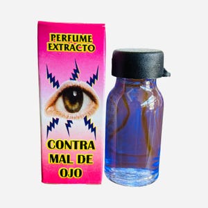 May include: A small, clear glass bottle with a black cap, filled with blue liquid, next to a pink box. The box has text that reads "PERFUME EXTRACTO" and "CONTRA MAL DE OJO" with an eye graphic and lightning bolts. The bottle has measurement markings.