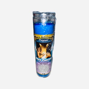 May include: A blue glass candle with a silver lid. The label reads "Veladora Original Abre Puertas" and includes text in Spanish about opening doors for love and work.
