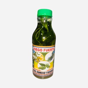 May include: A green glass bottle with a green lid filled with a green liquid and herbs. The label reads "RIEGO FUERTE" and "RUDA, ROMERO Y ALBAHACA" with a picture of three different herbs.