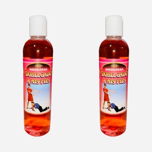 May include: Two clear glass bottles with red liquid and a pink label. The label says "ORIGINAL DOBLEGADO A MIS PIES" and features a cartoon image of a woman standing over a man lying on the ground.