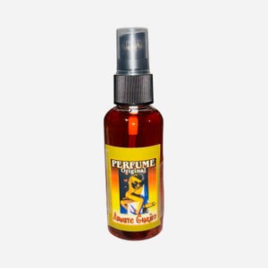 May include: A small, clear glass bottle with a black spray nozzle and a yellow label that reads "PERFUME Original Amate Guajiro". The label features a colorful illustration of a woman.