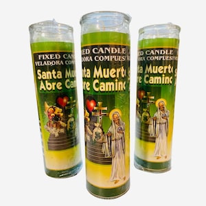 Puede incluir: Tres frascos de vela de vidrio verde y amarillo con una etiqueta blanca. La etiqueta tiene el texto "ED CANDLE VELADORA COMPUESIVE" y "Santa Muerte Abre Camino". Los frascos de vela tienen una imagen verde y amarilla de una figura de esqueleto con un corazón y una cruz.