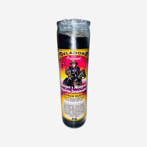 May include: A black glass candle with a pink and purple label. The label features a black and white illustration of a man on horseback holding a scythe. The text on the label reads "VELADORA Original Antiguo y Milagroso Spiritu Dominador CITRUN NUEVE SON EL PODER QUE HACE QUE MI ESPIRITU DOMINANTE TE HA DADO HAZ QUE"