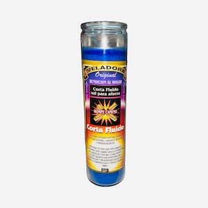May include: A blue glass candle with a label that reads "VELADORA Original BENDICION AL HOGAR Corta Fluido sal para afuera." The candle has a blue wax interior and is designed to be used for spiritual purposes.