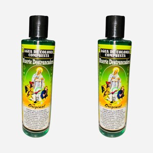 May include: Two green glass bottles with black caps. The bottles are labeled "Agua de Colonia Compuesta Muerte Destrancader" and "Original". The labels also feature a religious image.