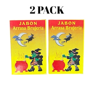 Pode incluir: Dois pacotes de sabonete com fundo amarelo e o texto "2 PACK". Cada embalagem apresenta uma ilustração de bruxa com um caldeirão e as palavras "JABON Arrasa Brujería". O design inclui uma lua crescente e uma bruxa em uma vassoura.
