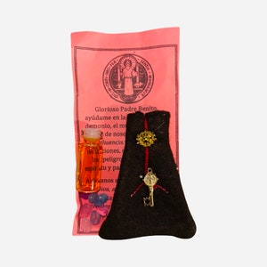Puede incluir: Un paquete de papel rosa y blanco con una pequeña bolsa negra, una pequeña botella de líquido naranja y algunas pequeñas cuentas de vidrio. El paquete tiene una imagen de un santo y el texto "Glorioso Padre Benito, ayúdame en la demonio, el mu de noso fluencia tentaciones, los peligro espíritu y pa Avianos Ay a Dios, n er a".