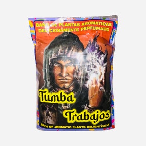 May include: A purple and yellow bag of bath salts with a drawing of a man in a hooded robe holding a glowing orb. The bag says "Baño de Plantas Aromaticas Deliciosamente Perfumado" and "Tumba Trabajos" with the text "Bath of Aromatic Plants Delightfully" at the bottom.