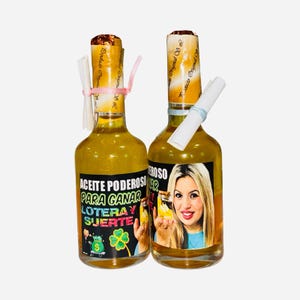 May include: Two glass bottles filled with a yellow liquid. Each bottle has a label with Spanish text and an image of a woman. The bottles are topped with rolled paper and tied with ribbons. The labels include the words "Aceite Poderoso" and "Loteria y Suerte."