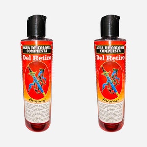 May include: Two red glass bottles of cologne with black caps. The bottles have a red and yellow label with the text "Agua de Colonia Compuesta Del Retiro Original" and a picture of two crossed swords.