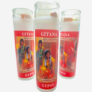 Puede incluir: Tres frascos de velas de vidrio rojo y blanco con las palabras "Gitana" y "Gypsy" impresas en ellos. Las velas presentan una imagen colorida de tres mujeres con ropa tradicional.