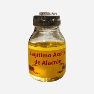 May include: A small glass bottle filled with a yellow liquid. The bottle has a red label that reads "Legítimo Aceite de Alacrán".