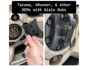 Op de afbeelding: Close-up van een zwarte plastic naafvergrendeling met een zilveren schroef. De naafvergrendeling is bevestigd aan een zilveren velg. De tekst "Tacoma, 4Runner, & other OEMs with Aisin Hubs" is zichtbaar in de afbeelding.