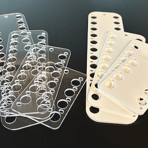 May include: Set of clear and white acrylic needle organizers with multiple rows of holes for storing needles.