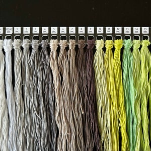 May include: A color chart of DMC embroidery floss, showing 17 different shades of white, gray, beige, brown, yellow, and green.