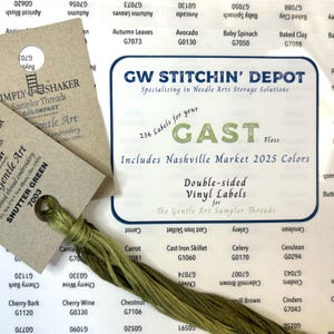 May include: A close-up of a white label with the text "GW Stitch'n Depot" and "Specializing in Needle Arts Storage Solutions". The label also includes the text "236 Labels for your GAST Floss" and "Includes Nashville Market 2025 Colors". Below the text is a smaller label that says "Double-sided Vinyl Labels for The Gentle Art Sampler Threads".
