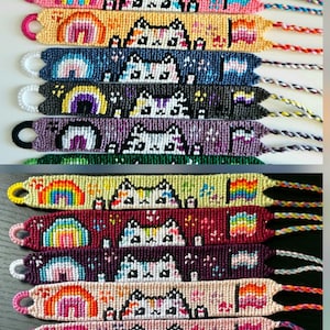 May include: A collection of sixteen woven friendship bracelets featuring a repeating pattern of a cat face, a rainbow, and a small flag. Each bracelet is crafted with colourful embroidery thread and includes a braided tie at one end for closure.