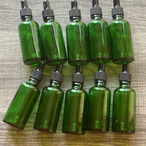 May include: Ten green glass bottles with black dropper tops. The bottles are arranged in two rows of five.