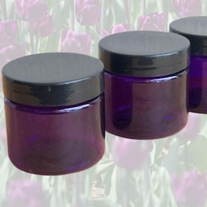 May include: Three purple glass jars with black lids. The jars are empty and have a smooth, rounded shape.