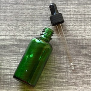 Peut inclure: Une bouteille en verre vert avec un bouchon compte-gouttes noir. La bouteille est vide et pr&ecirc;te &agrave; &ecirc;tre remplie d'huiles essentielles ou d'autres liquides.